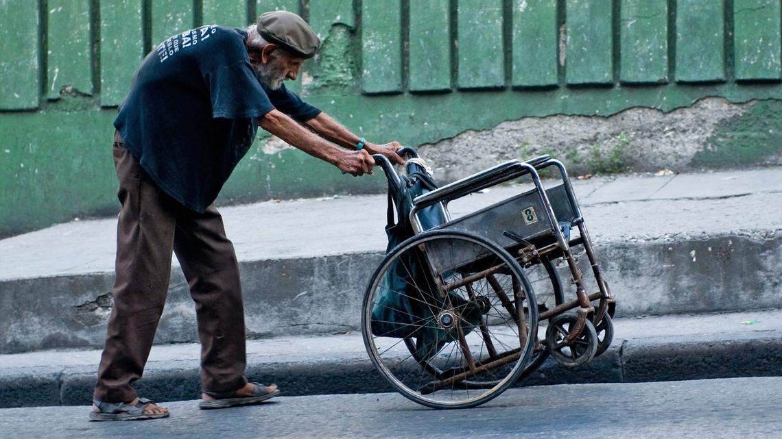 Un anciano empuja una silla de ruedas en Holguín, Cuba.