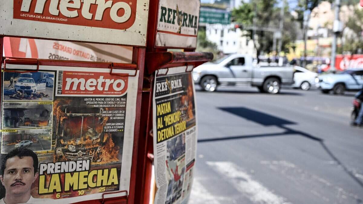 The front page of a local newspaper displays news about the death of Nemesio Oseguera, alias "El Mencho," Mexico's most wanted drug lord in recent years, in Mexico City on February 23, 2026. Mexico has deployed 10,000 troops to quell clashes sparked by the killing of the country's most wanted drug lord, which have left dozens dead, officials said on February 23. Nemesio "El Mencho" Oseguera, leader of the Jalisco New Generation Cartel (CJNG), was wounded on February 22 in a shootout with soldiers in the town of Tapalpa in Jalisco state and died while being flown to Mexico City, the army said. (Photo by Yuri CORTEZ / AFP via Getty Images)