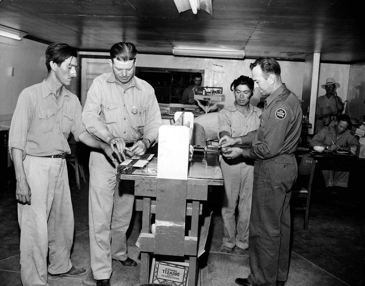 Dos inmigrantes mexicanos, Pedro Vidal, izquierda, y Canuto García, derecha, mientras les toman las huellas dactilares los inspectores de la Patrulla Fronteriza de EEUU Paul Watson, izquierda, y N. Franklin Davidson, derecha, en un campo de detención en El Centro, California, el 11 de agosto, 1951. Después del procesamiento, serían llevados en avión a Sinaloa, México.