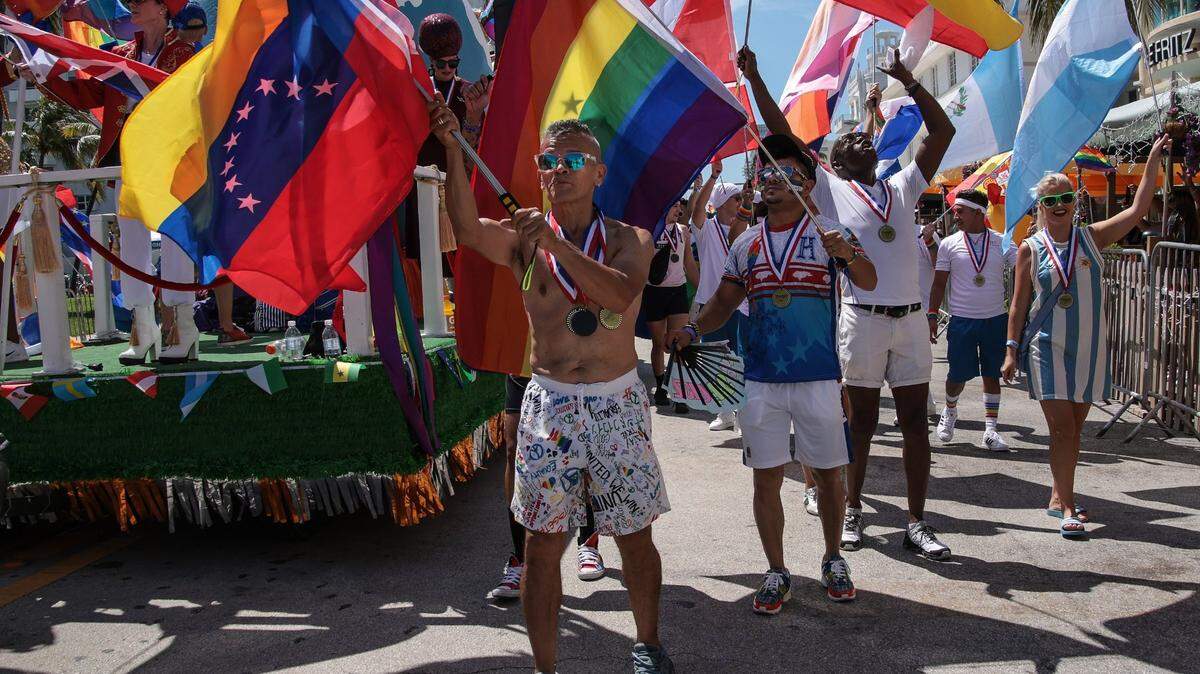 Miguel Barráis and others wave flags as they walk down Ocean Drive during the Miami Beach Pride Parade in 2021.