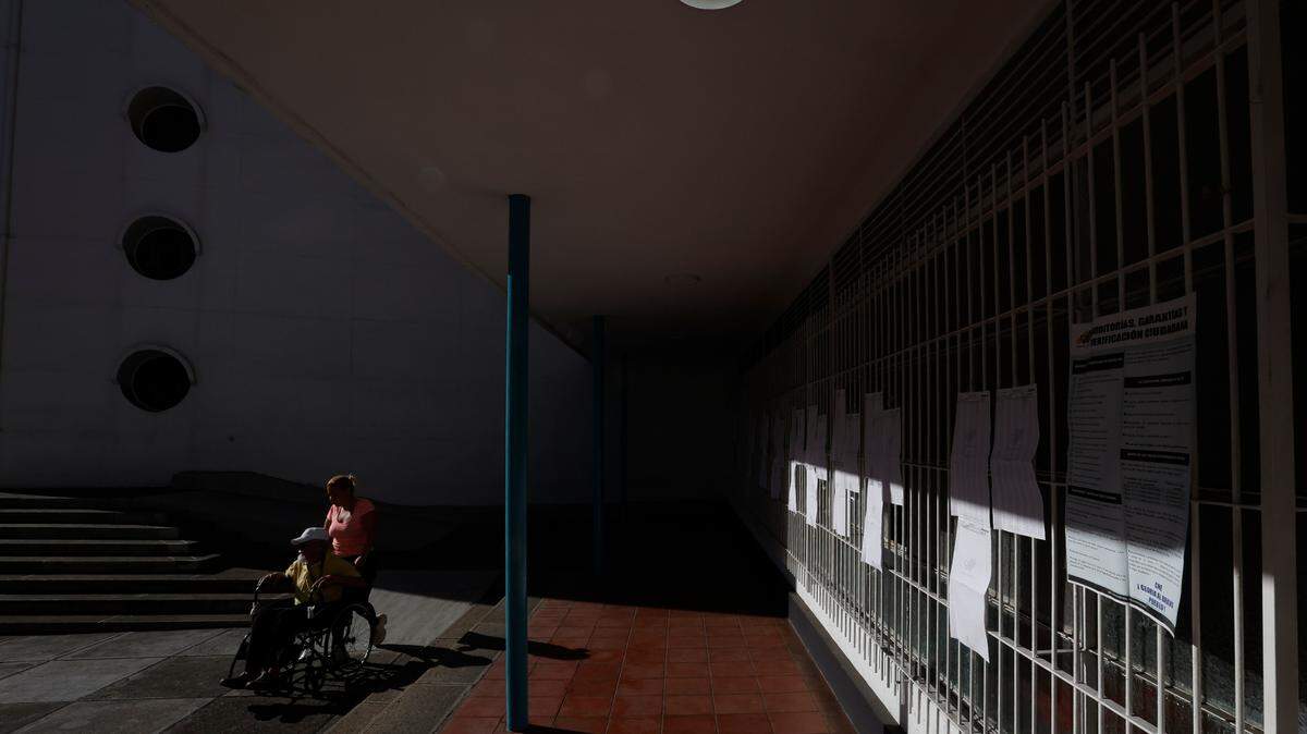 Un hombre en una silla de ruedas y una mujer esperan en un centro electoral para votar en el referendo sobre el Esequibo, el domingo 3 de diciembre de 2023.