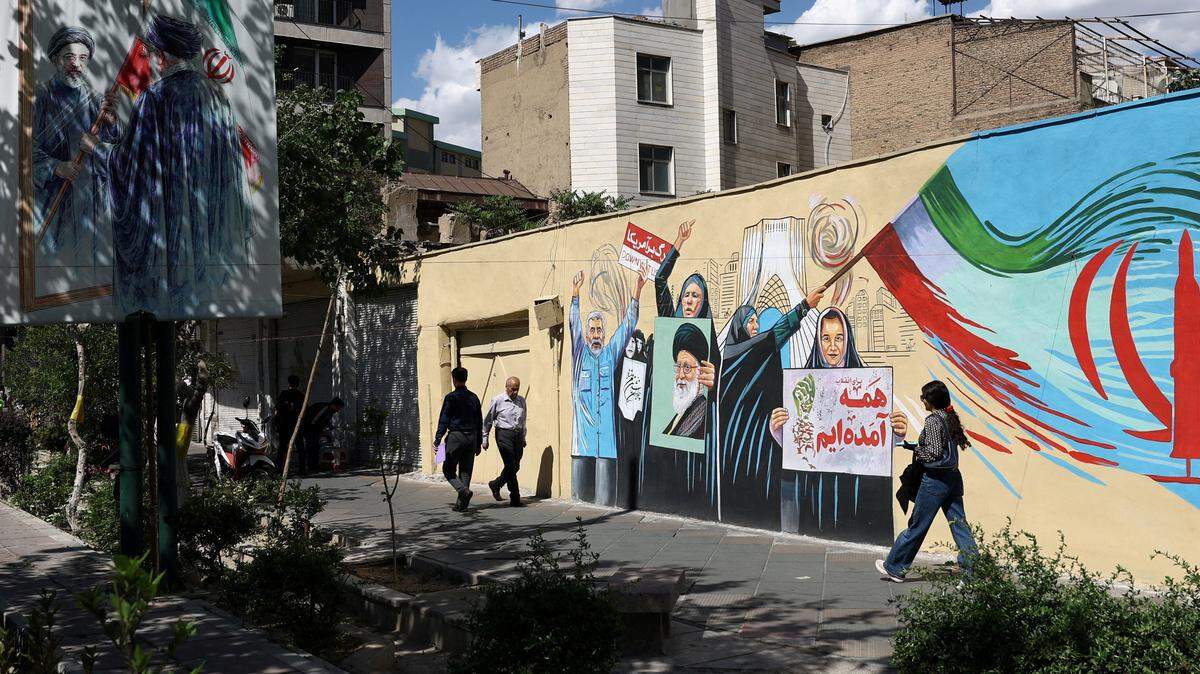 Varias personas caminan por una calle cerca de un mural con la imagen del difunto Líder Supremo de Irán, el ayatolá Ali Khamenei, en Teherán, Irán, el 18 de mayo de 2026.