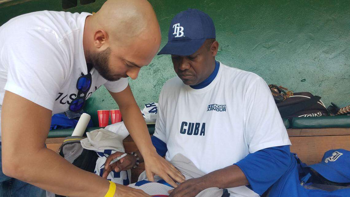 OMAR LINARES firma un jersey suyo al experto en temas de pelota cubana William Perez Villalba el 24 de noviembre en Tampa.