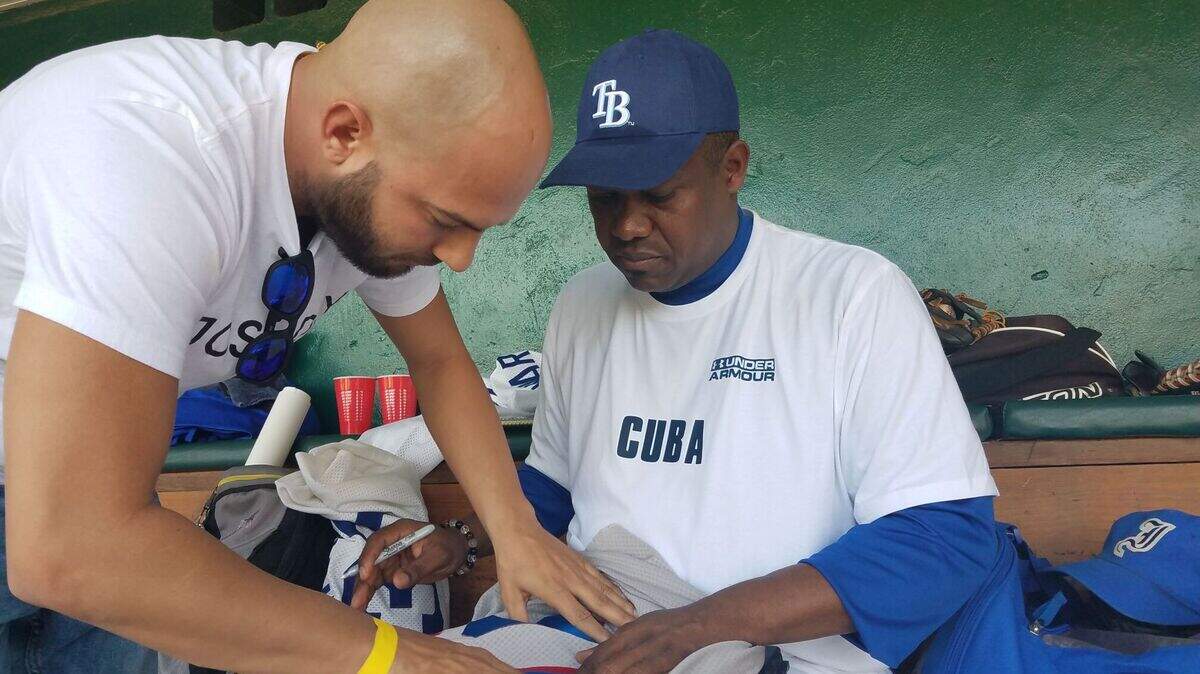 OMAR LINARES firma un jersey suyo al experto en temas de pelota cubana William Perez Villalba el 24 de noviembre en Tampa.