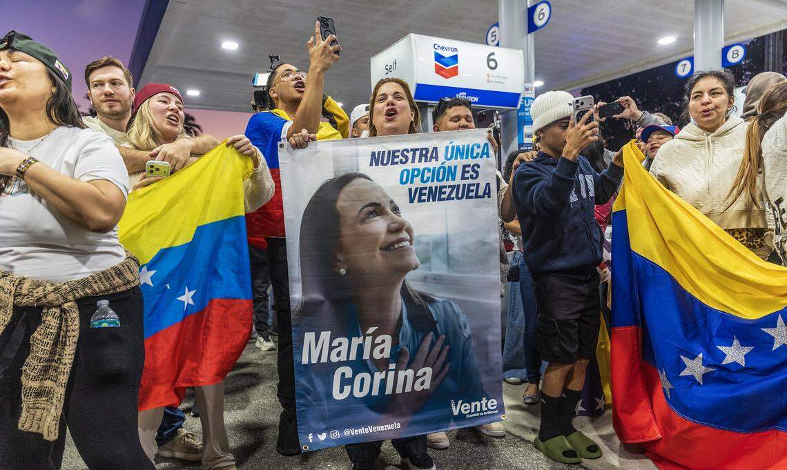 Lisbeth García muestra una pancarta con una foto de la líder opositora María Corina Machado mientras se une a un grupo de exiliados venezolanos que viven en el sur de Florida, quienes celebran frente a El Arepazo en Doral, Florida, después de que Estados Unidos capturara al líder venezolano Nicolás Maduro, el 3 de enero de 2026.