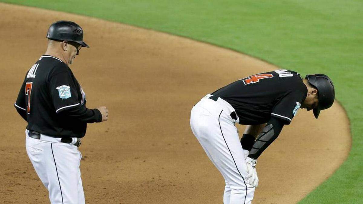 MARTIN PRADO intenta contener el dolor, mientras el coach de primera base Perry Hill va en su ayuda.
