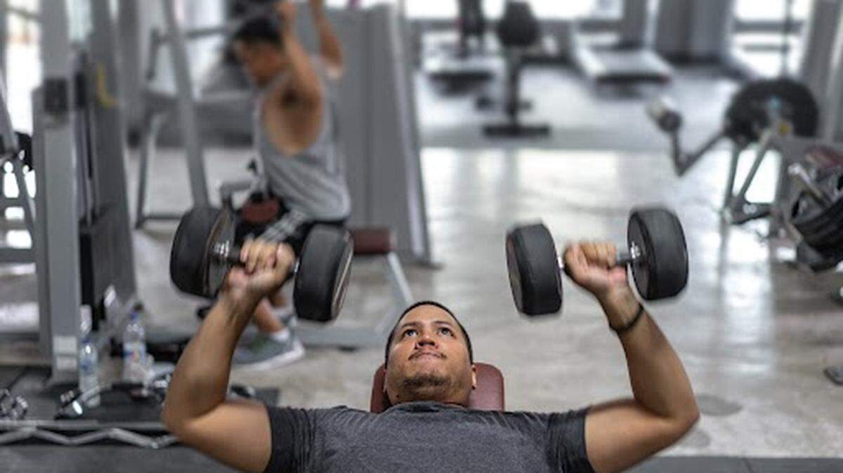 Un hombre levanta pesas en un gimnasio.