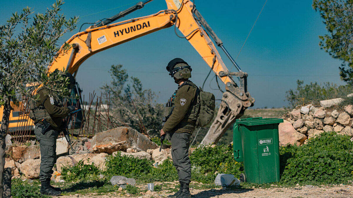 Soldados israelíes montan guardia mientras una excavadora trabaja en la aldea de Beit Awwa, cerca de Hebrón, en la Cisjordania ocupada, el jueves 5 de febrero de 2026. Las fuerzas israelíes demolieron partes de dos viviendas palestinas en Beit Awwa, alegando que la construcción se encontraba cerca de la barrera de separación.