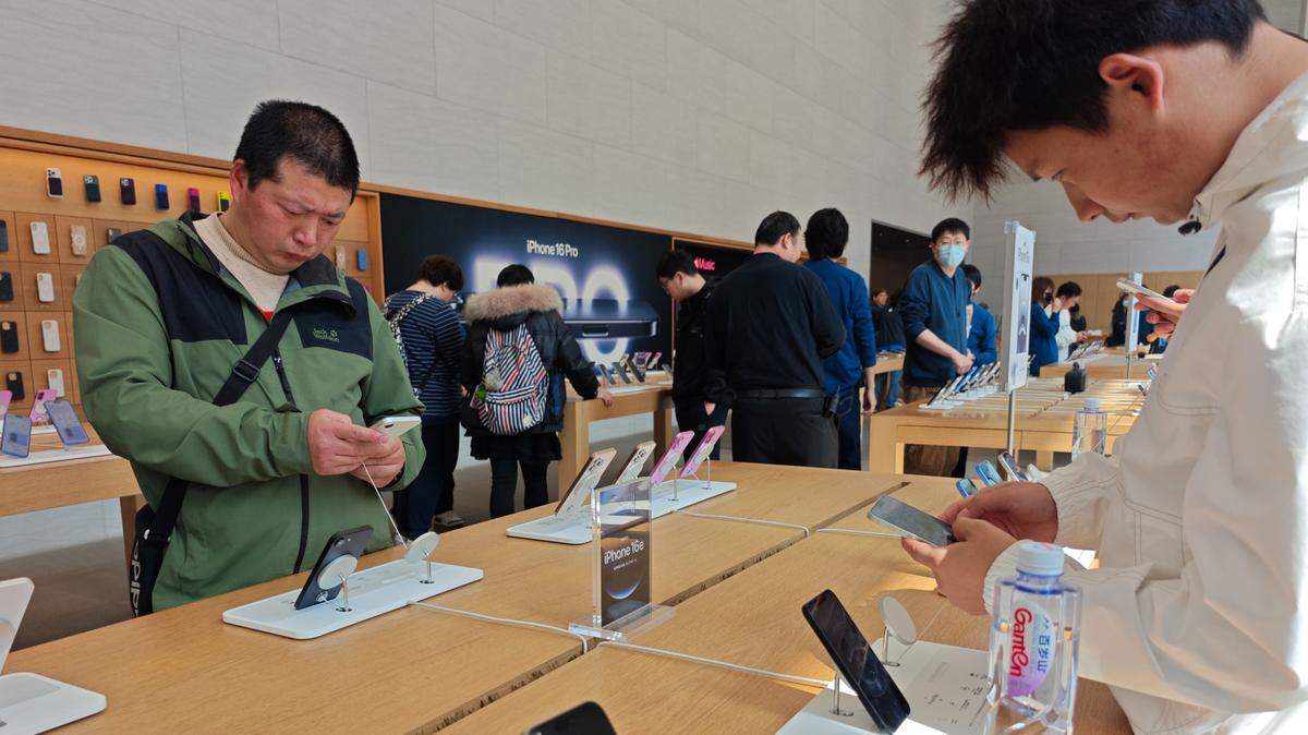 Varios clientes examinan los ‘smartphones’ Apple iPhone 16e en una tienda de Shanghai, China, el 28 de febrero de 2025.