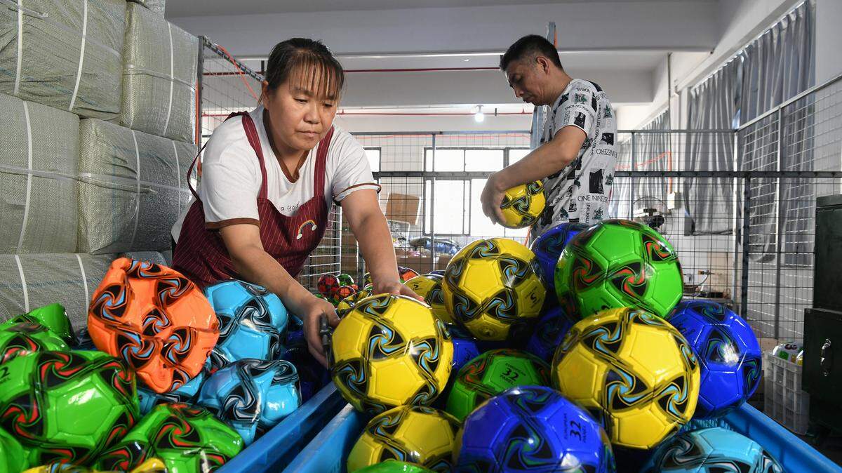 Dos trabajadores inflan balones de fútbol en una empresa local de artículos deportivos en Yiwu, provincia de Zhejiang, China, el 15 de septiembre de 2025.