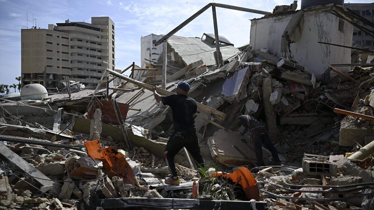 Hombres buscan entre los escombros de edificios colapsados para recuperar pertenencias tras el terremoto ocurrido en Catia La Mar, estado La Guaira, a unos 30 kilómetros al noroeste de Caracas, el 25 de junio de 2026. El doble terremoto, el más fuerte registrado en Venezuela en más de un siglo, ha dejado al menos 164 muertos y destruyó numerosos edificios cerca de la capital, donde familiares y vecinos continúan buscando a personas desaparecidas.