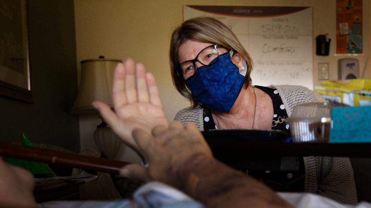 Suncoast Hospice Spiritual Care Coordinator Victoria Long talks with a hospice resident Tuesday, May 19, 2020 in St. Petersburg, Fla. (John Pendygraft/Tampa Bay Times via AP)