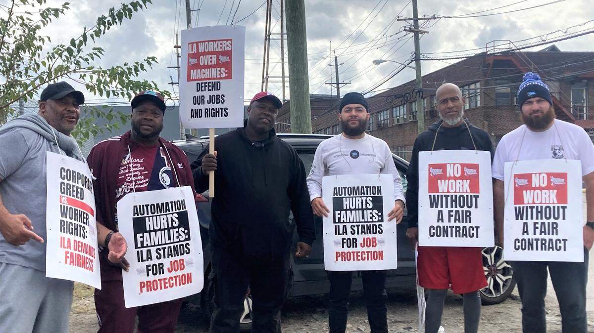 Trabajadores portuarios en huelga muestran pancartas exigiendo mejoras salariales en Camden, Nueva Jersey, el martes 1 de octubre de 2024.