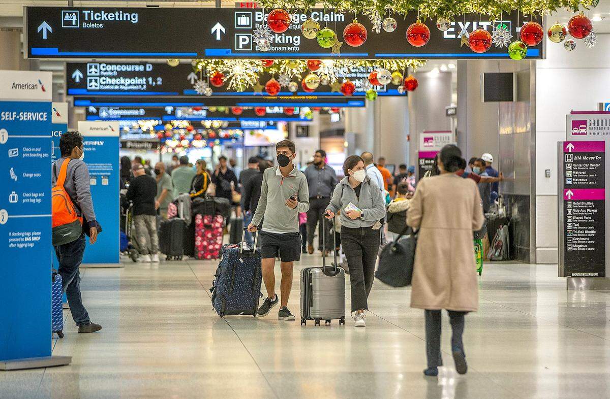 Decenas de viajeros caminan por los pasillos del Aeropuerto Internacional de Miami, el jueves 23 de diciembre, donde un centro de pruebas de Covid está completamente ocupado ya que las infecciones por COVID-19 están aumentando en todo el sur de Florida durante las vacaciones.