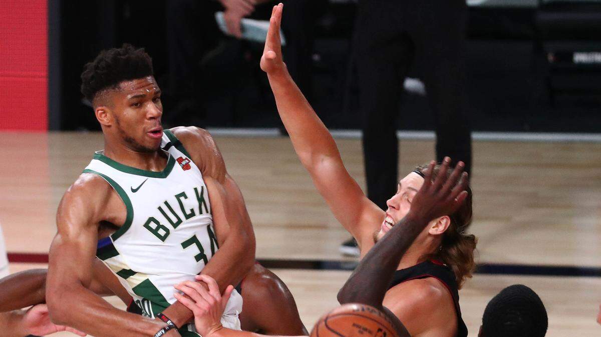 La estrella de los Bucks de Milwaukee Giannis Antetokounmpo pasa la pelota ante la marca de Kelly Olynyk #9 y Kendrick Nunn #25, del Heat de Miami, en el partido celebrado el 6 de agosto de 2020 en Lake Buena Vista, Florida.