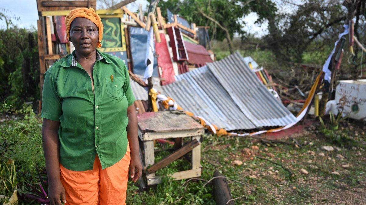 Celia Coke stands next to her shop, destroyed after the passage of Hurricane Melissa in the Wilton district of St. Elizabeth, Jamaica on October 29, 2025. Hurricane Melissa ripped up trees and knocked out power after making landfall in Jamaica on October 28, 2025 as one of the most powerful hurricanes on record, inundating the island nation with rains that threaten flash floods and landslides. (Photo by Ricardo MAKYN / AFP) (Photo by RICARDO MAKYN/AFP via Getty Images)