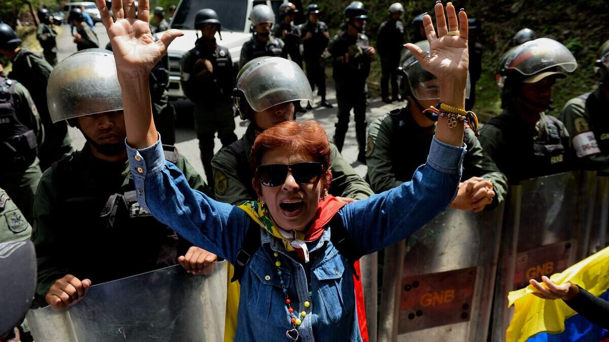 An activist opposing Venezuelan President Nicolas Maduro shouts slogans as security forces block their access to the funeral of Jose Diaz Pimentel and Abraham Agostini, two of the six other dissidents gunned down along with former elite police officer Oscar Perez in a bloody police operation, at a cemetery in Caracas on January 20, 2018.
Perez, Venezuela's most wanted man since June when he flew a stolen police helicopter over Caracas dropping grenades on the Supreme Court and opening fire on the Interior Ministry, had gone on social media while the operation was under way on January 16 to say he and his group wanted to surrender but were under unrelenting sniper fire. That has raised questions about the government's account that the seven were killed after opening fire on police who had come to arrest them. / AFP PHOTO / Federico PARRA        (Photo credit should read FEDERICO PARRA/AFP via Getty Images)