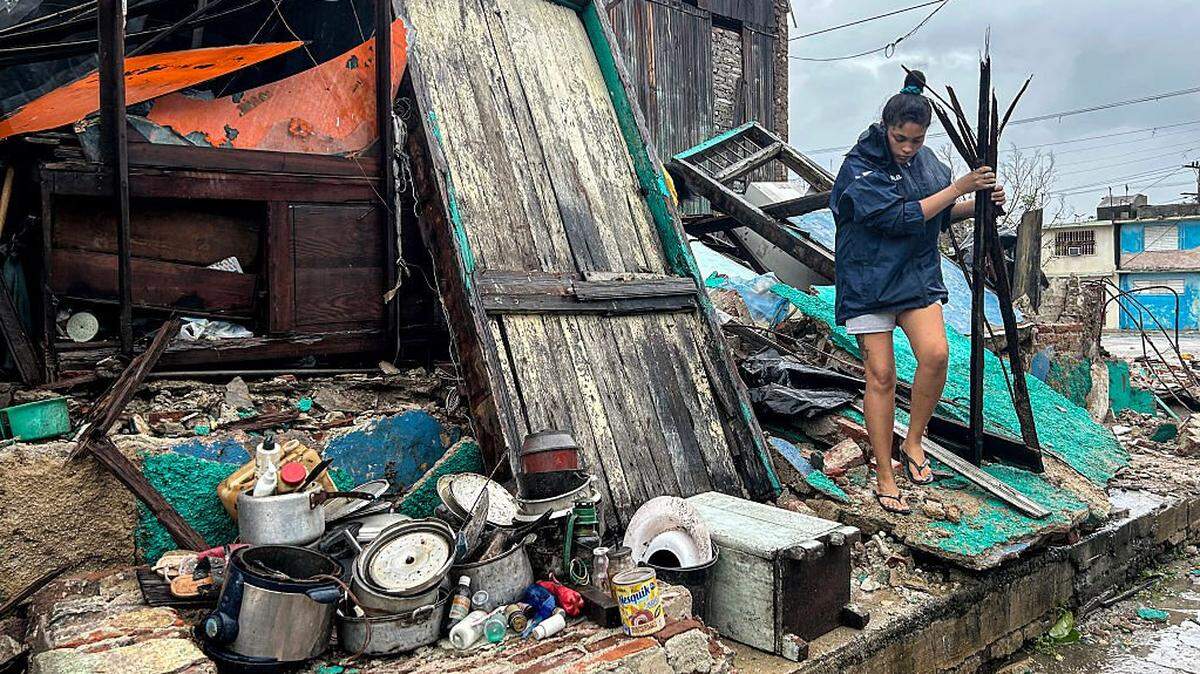 A woman salvages belongings from the rubble of her home after it collapsed during Hurricane Melissa's passage through Santiago de Cuba, Cuba, on October 29, 2025. A powerful Hurricane Melissa made landfall in eastern Cuba on Wednesday, causing damage and flooding to homes and streets in Santiago de Cuba province, an AFP team on the ground reported. (Photo by YAMIL LAGE / AFP) (Photo by YAMIL LAGE/AFP via Getty Images)
