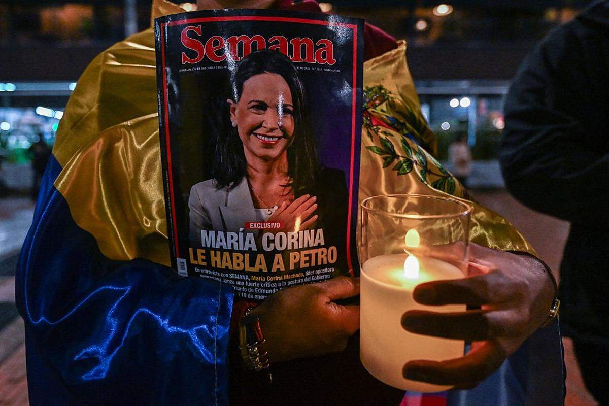 A Venezuelan citizen holds a magazine cover featuring the image of Nobel Laureate Maria Corina Machado reading "Maria Corina speaks to Petro," referring to Colombian President Gustavo Petro, during a vigil in support of Machado in Bogota on December 6, 2025. Venezuelan opposition leader MarÃ­a Corina Machado, who lives in hiding in her country, confirmed that she will be in Oslo next week to receive her Nobel Peace Prize, the director of the Nobel Institute announced to AFP on Saturday. (Photo by Luis ACOSTA / AFP via Getty Images)