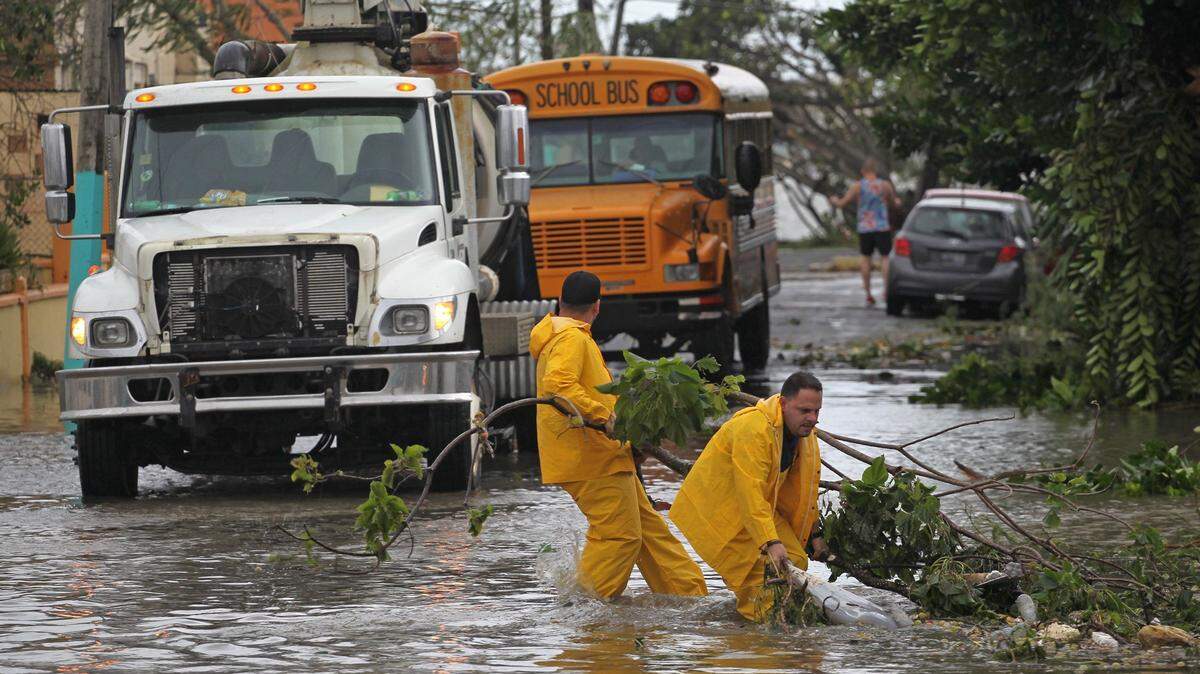 Dos hombres retiran escombros del huracán de la inundada rampa de la carretera PR888 cuando la ciudad comienza su recuperación. Las calles inundadas, las líneas eléctricas y los árboles caídos y la daños a la propiedad son algunas de las secuelas del huracán María, que tocó tierra como huracán categoría 4 en San Juan, Puerto Rico, el miércoles 20 de septiembre de 2017.