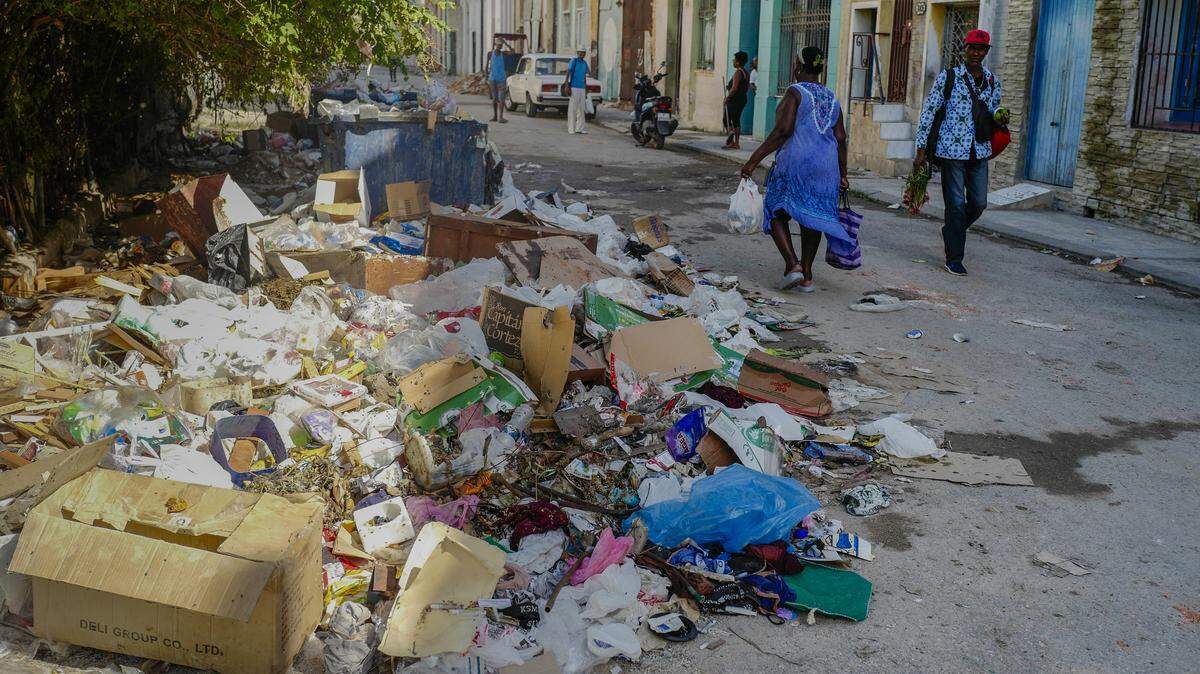 Residentes del barrio habanero de Jesús María evitan montañas de basura para seguir su paso, en medio de una grave crisis de salubridad que contribuye a la propagación de virus como el oropouche, chikungunya, dengue y otras enfermedades causadas por la picadura del mosquito Aedes, el 20 de noviembre en Cuba.
