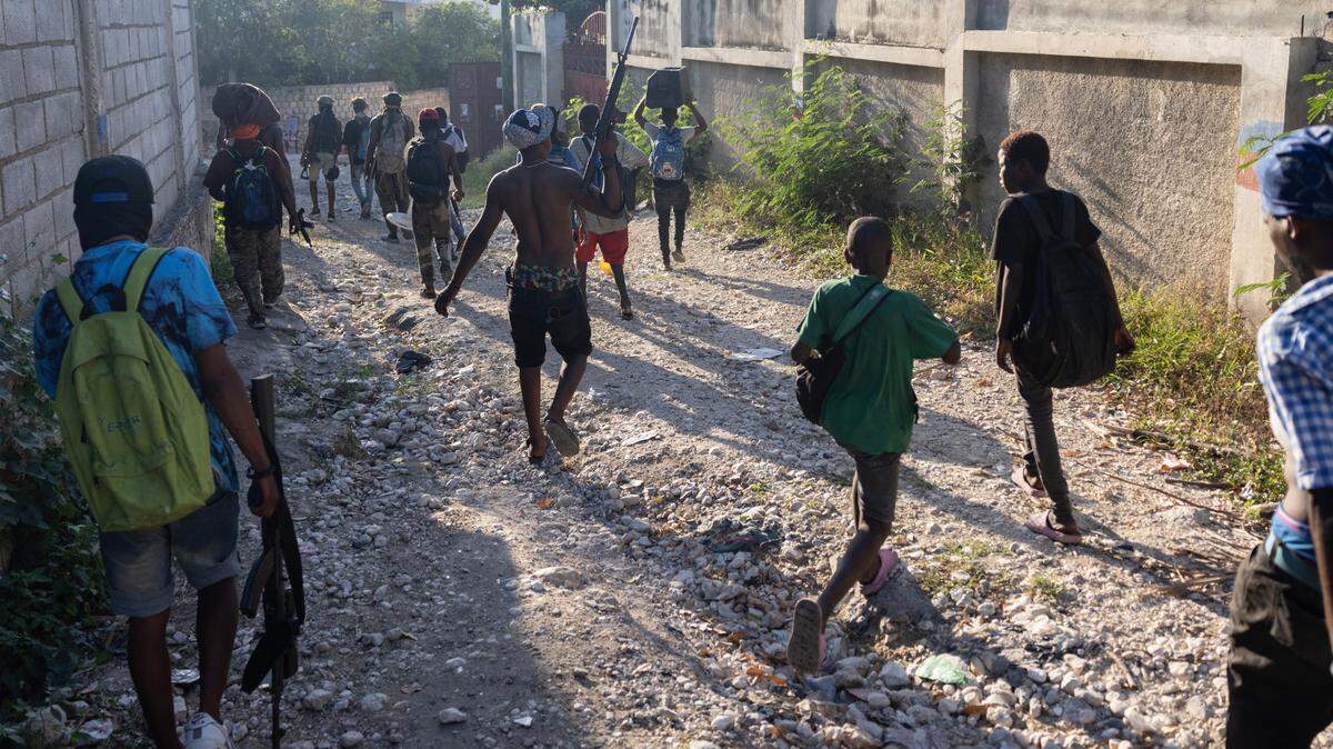  Miembros de pandillas cargan bienes robados después de asaltar un barrio de Puerto Príncipe el viernes, 6 de diciembre de 2024. Más de 1,000 escuelas han sido cerradas en Haití debido a la crisis de pandillas, y los niños a menudo llevan mochilas para llevar artículos que han encontrado o saqueado en lugar de útiles escolares. 