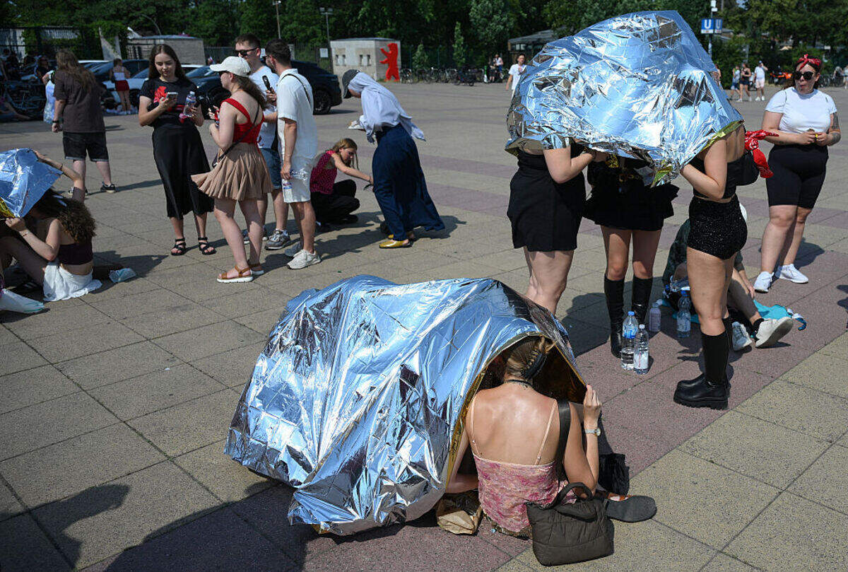 Personas utilizan mantas térmicas para protegerse del calor al llegar al Estadio Olímpico para un concierto del cantante estadounidense Bruno Mars el 28 de junio de 2026 en Berlín, ya que se prevé que la capital alemana alcance temperaturas cercanas a los 40 grados Celsius durante una ola de calor en Europa.