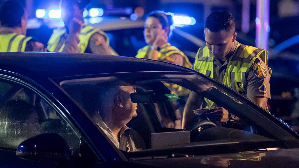 Un oficial de la Patrulla de Carreteras de Florida habla con un conductor en un puesto de control a lo largo de 5th Street el viernes 24 de marzo de 2023 en Miami Beach, Florida. Después de dos tiroteos mortales, los funcionarios de la ciudad votaron por no volver a imponer un toque de queda a medianoche, pero implementaron una orden de emergencia prohibir la venta de alcohol después de las 6 p.m.