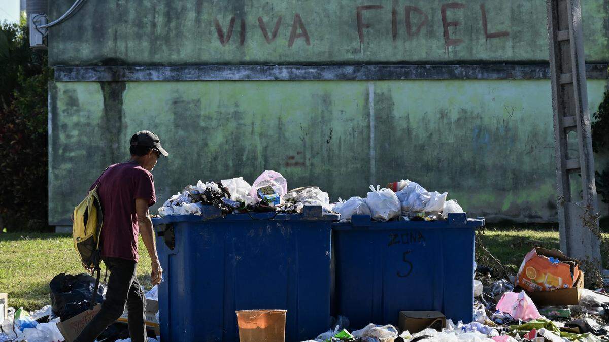 A man walks past a graffiti of the late Cuban leader Fidel Castro on a street in Havana on February 16, 2026. Cuba has a collapsed health system, which has suspended surgical operations and medical test due to blackouts, all amidst unsanitary conditions in the streets.