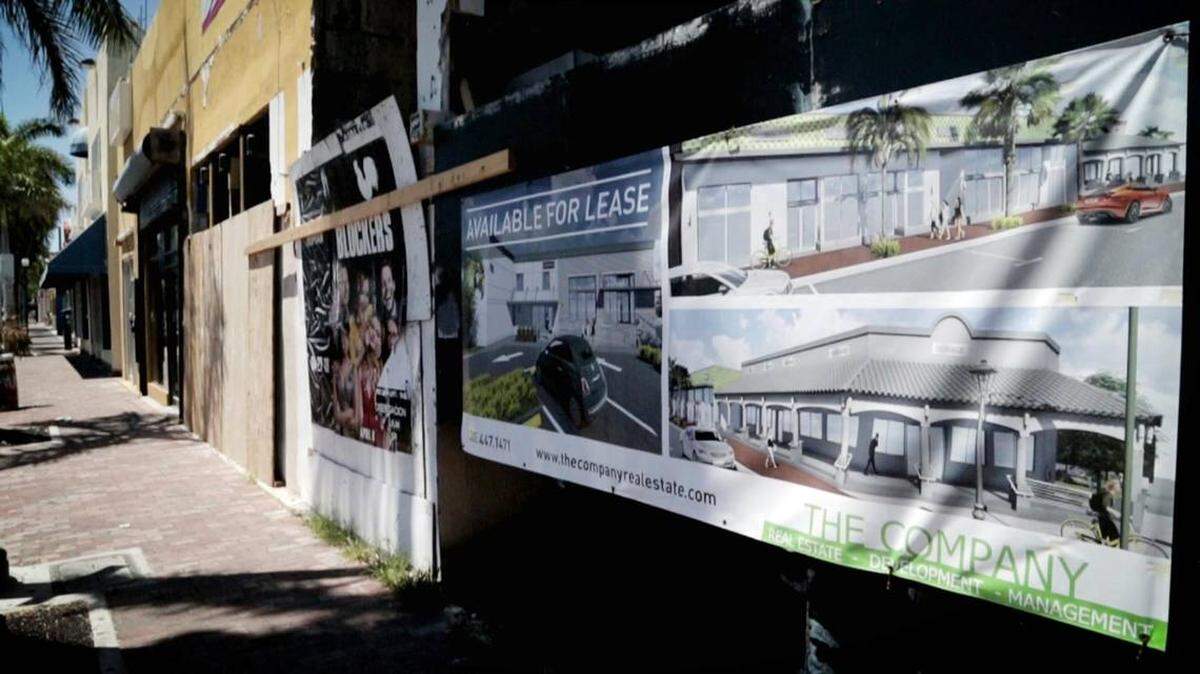 A sign illustrates the remodeling of an empty strip mall on Calle Ocho where only one business remains open.