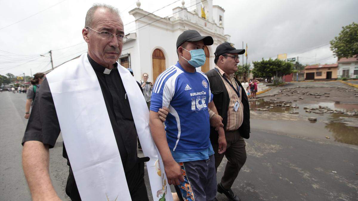 El sacerdote Edwin Román Calderón camina frente a la iglesia San Miguel Arcangel, junto a Danilo Martinez, de la Asociación Nicaragüense Pro Derechos Humanos (ANPDH), en Masaya, el 6 de junio. Román Calderón fue agredido por turbas del gobierno en la misma iglesia mientras oficiaba misa el 9 de septiembre.