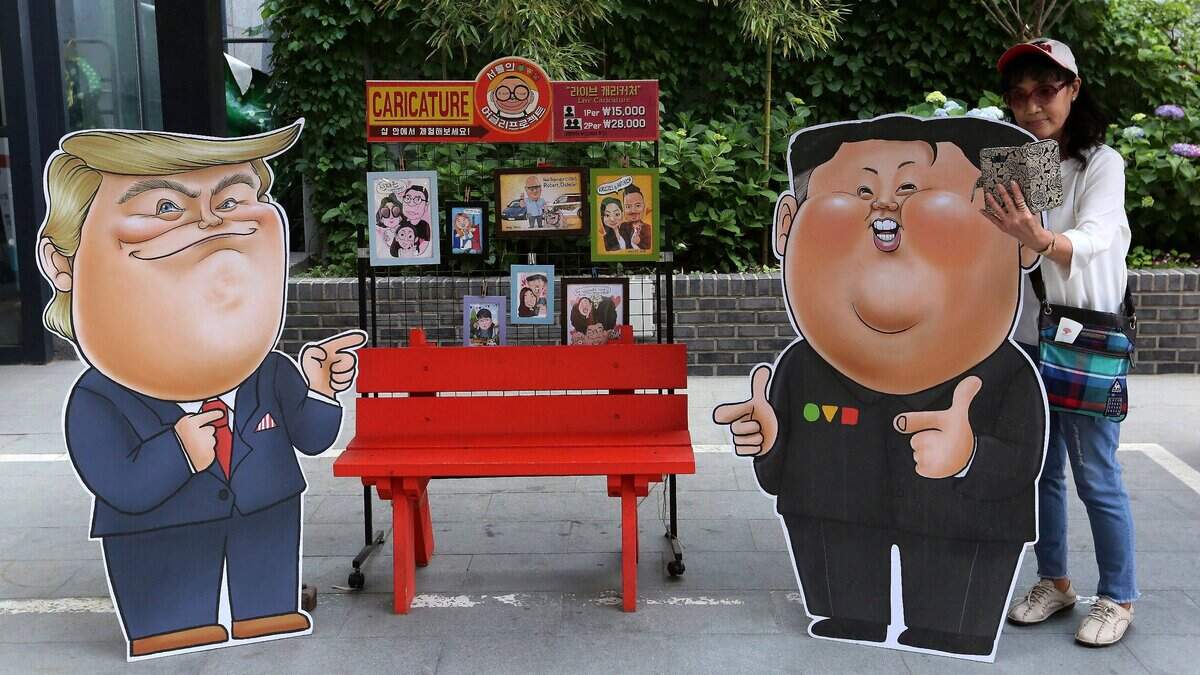 Una turista se toma fotos junto a dos caricaturas, una del presidente Trump y otra del líder norcoreano Kim Jong-un, el 26 de mayo del 2019 en Seúl, Corea del Sur.