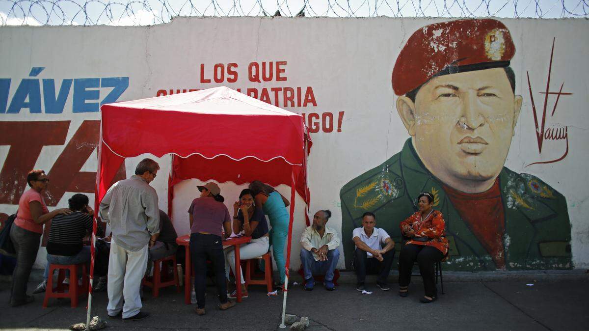 A group of people waits to vote in Caracas, Venezuela, in front of a mural of late President Hugo Chavez.