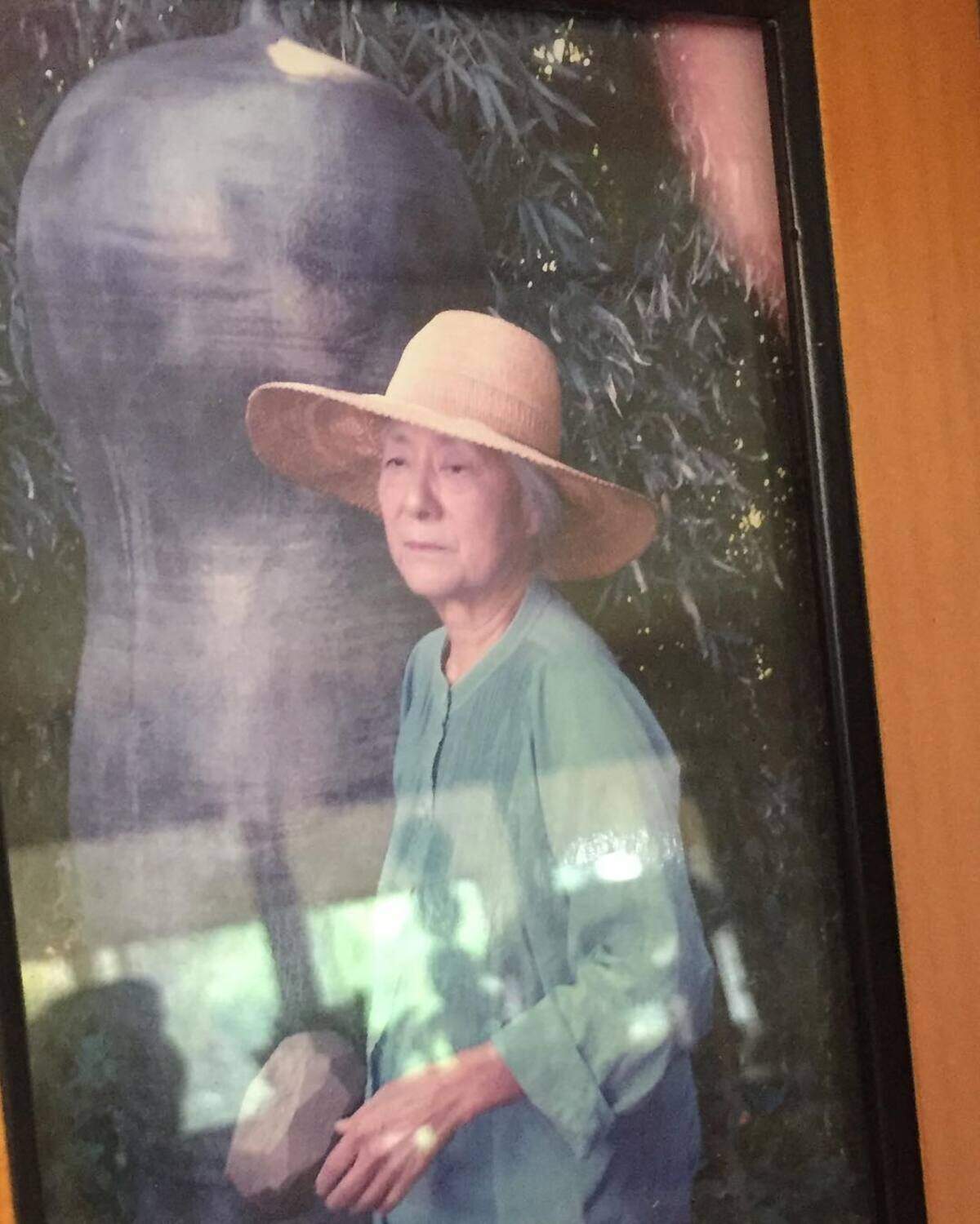 Toshiko Takaezu con uno de sus monumentales bronces reflejados en el cristal.