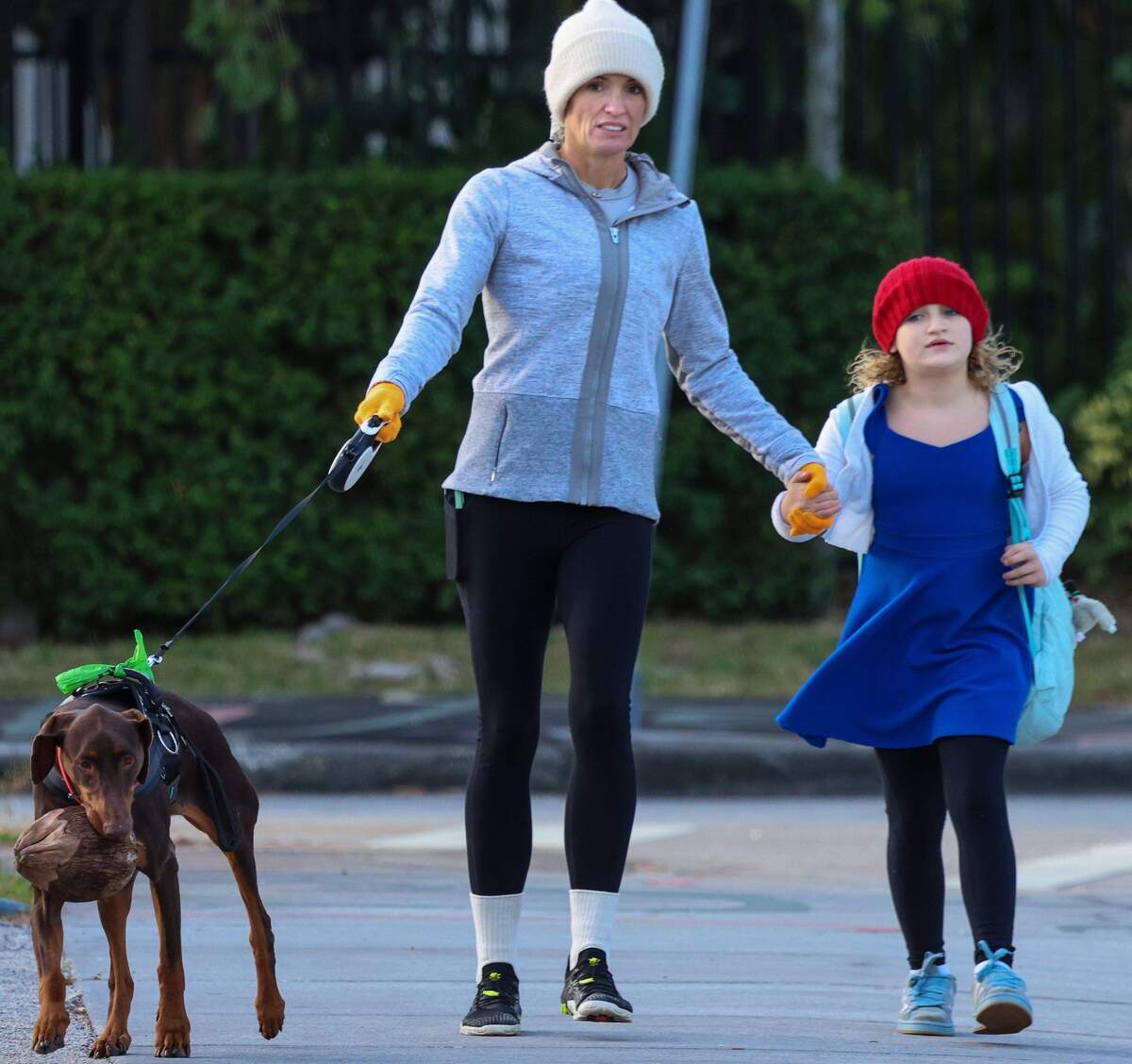 En medio del frío, una mujer no identificada acompañaba a un niño a la escuela Cushman mientras su perro llevaba un coco en la boca.
