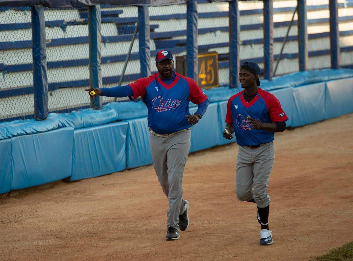 El entrenador de pitcheo Pedro Luis Lazo (izq.) corre con el lanzador Liván Moinelo en un entrenamiento en el estadio Latinoamericano en La Habana, Cuba, el 16 de enero de 2023.