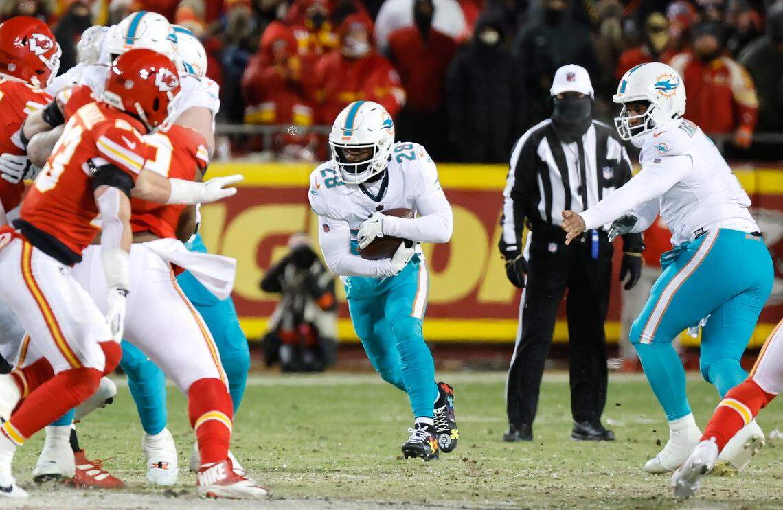 Miami Dolphins quarterback Tua Tagovailoa (1) hands the ball off running back De’Von Achane (28) during first half of an NFL wild-card playoff football game against the Kansas City Chiefs at GEHA Field at Arrowhead Stadium in Kansas City, Missouri, on Saturday, January 13, 2024.