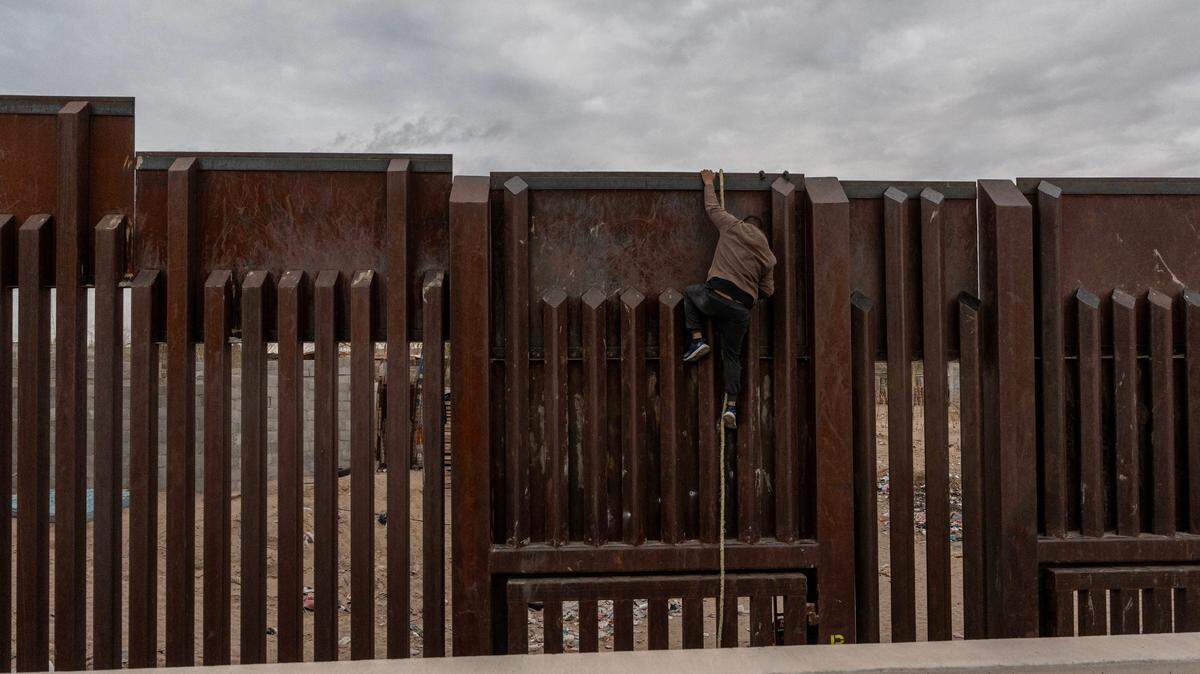 Un guía escala el muro fronterizo de regreso a México tras ser avistado por un agente de la Patrulla Fronteriza en Sunland Park, Nuevo México, el 16 de enero de 2025.