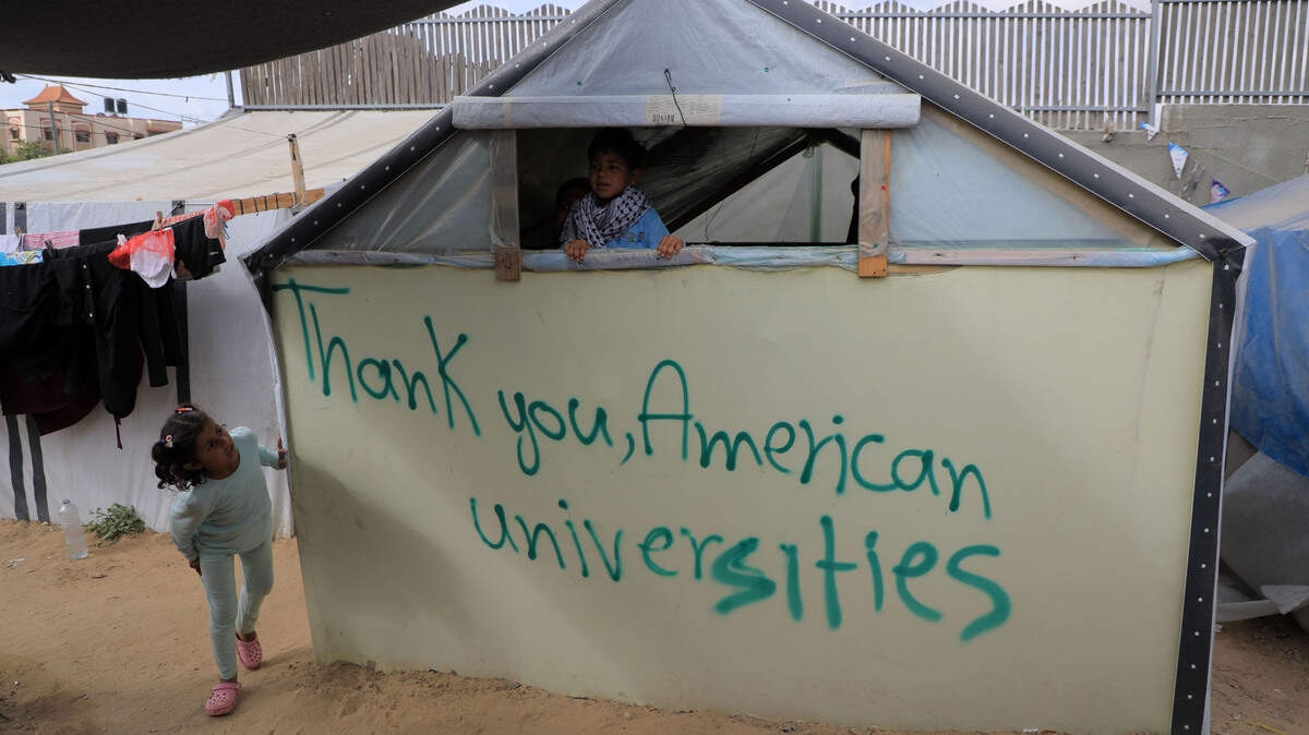 Una niña mira un mensaje escrito en una carpa que dice en inglés, “Gracias, universidades americanas”, en un campamento de desplazados en Rafah, en el sur de Gaza, el domingo 28 de abril de 2024.