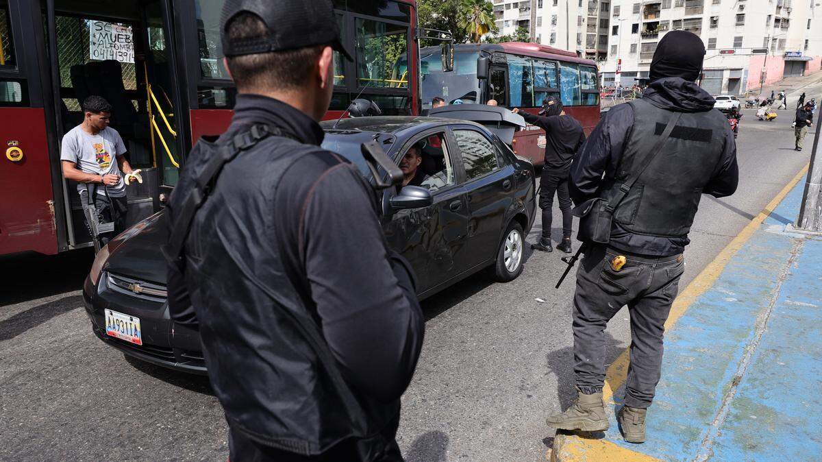 Miembros armados del Colectivo inspeccionan el maletero de un automóvil después de que se escucharan explosiones y aeronaves a baja altura en las primeras horas del 3 de enero de 2026 en Caracas, Venezuela.