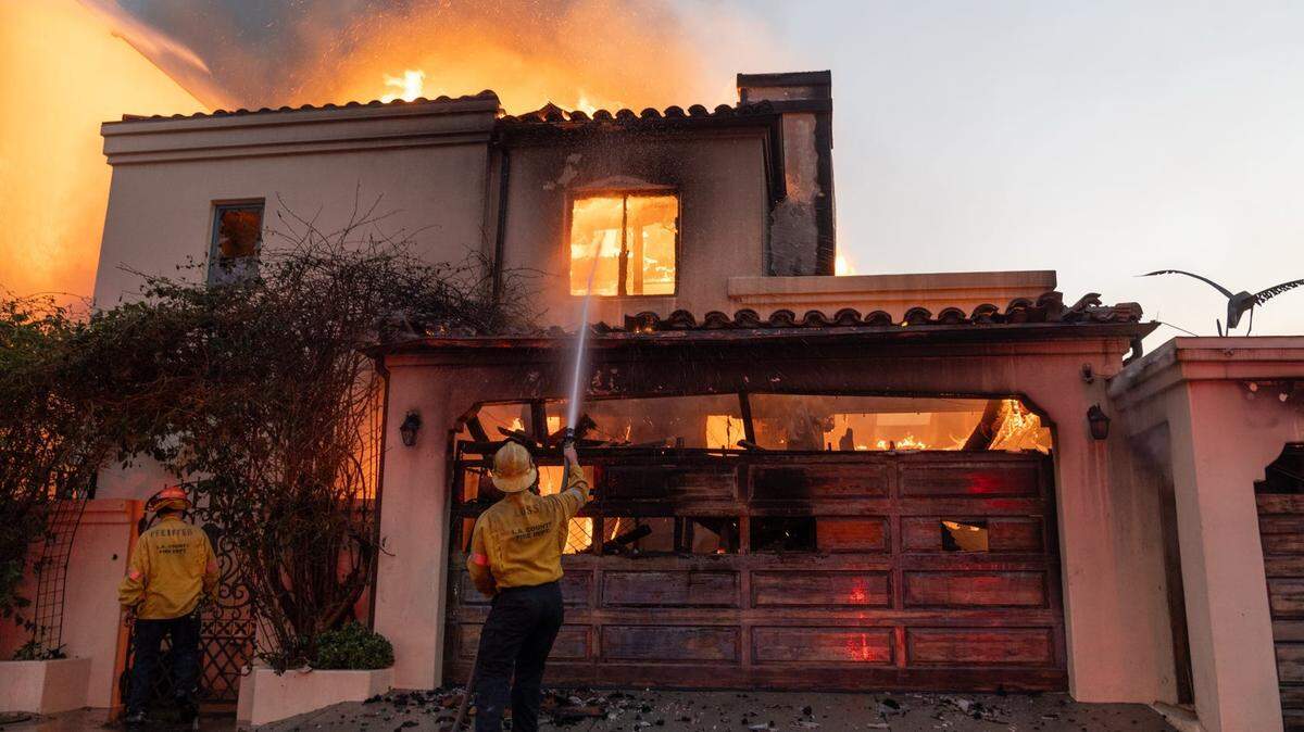 Bomberos intentan extinguir un incendio en una casa en el vecindario de Pacific Palisades, Los Angeles, el 8 de enero de 2025.