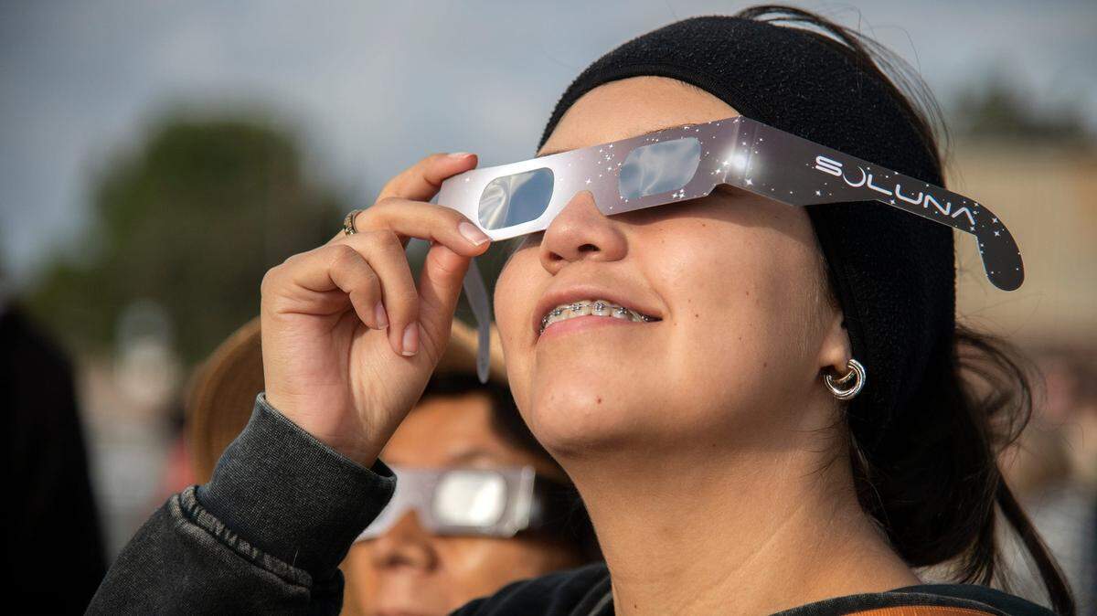 Una espectadora usa lentes especiales para ver un eclipse solar en octubre de 2023, en el campus de San Joaquin Delta College in Stockton, California.