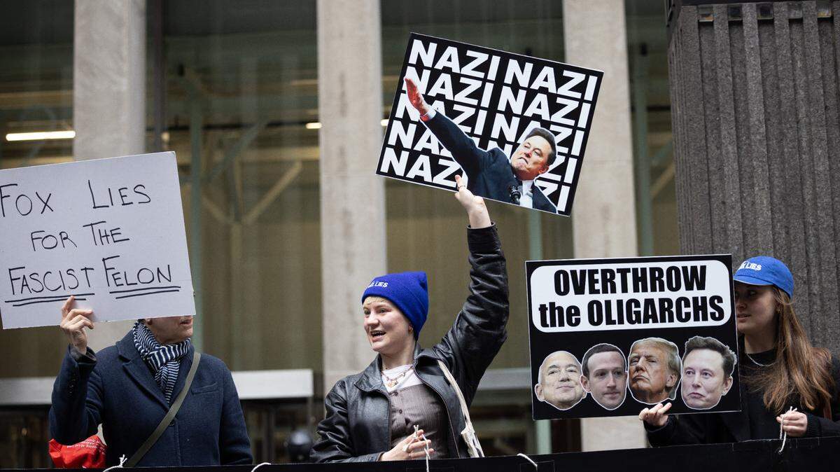 Decenas de manifestantes participan en una protesta llamada “Detengan a Musk” (Stop Musk), frente a la sede del canal conservador de noticias Fox News, en Nueva York, el martes 25 de febrero de 2025. Una mujer muestra una pancarta con la cara de Elon Musk y la palabra “nazi” (centro), otra dice “Fox News miente por el delincuente fascista” (izq.), y la tercera dice “Derroquemos a los oligarcas”.