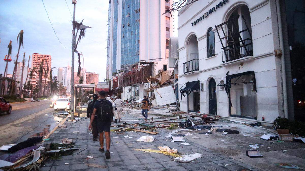 Varias personas caminan frente a un hotel en Acapulco, México, que fue impactado por los devastadores vientos del huracán Otis, el miércoles 25 de octubre de 2023.