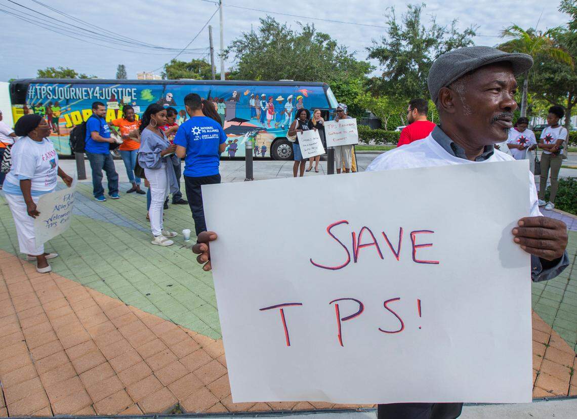 In this file photo, Michel Bien-Aime holds a sign “Save TPS” when a bus from National TPS Alliance arrived at the Little Haiti Cultural Center in Miami.