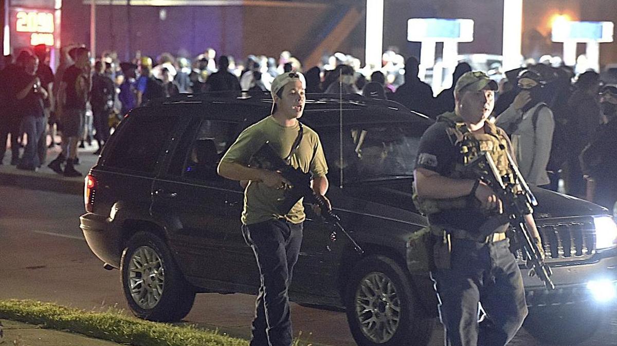 Kyle Rittenhouse, left, with backwards cap, walks along Sheridan Road in Kenosha, Wis., with another armed civilian. A Republican student group at Arizona State University is receiving backlash for donating money to Rittenhouse, the 17-year-old gunman who fatally shot two protesters in Wisconsin.