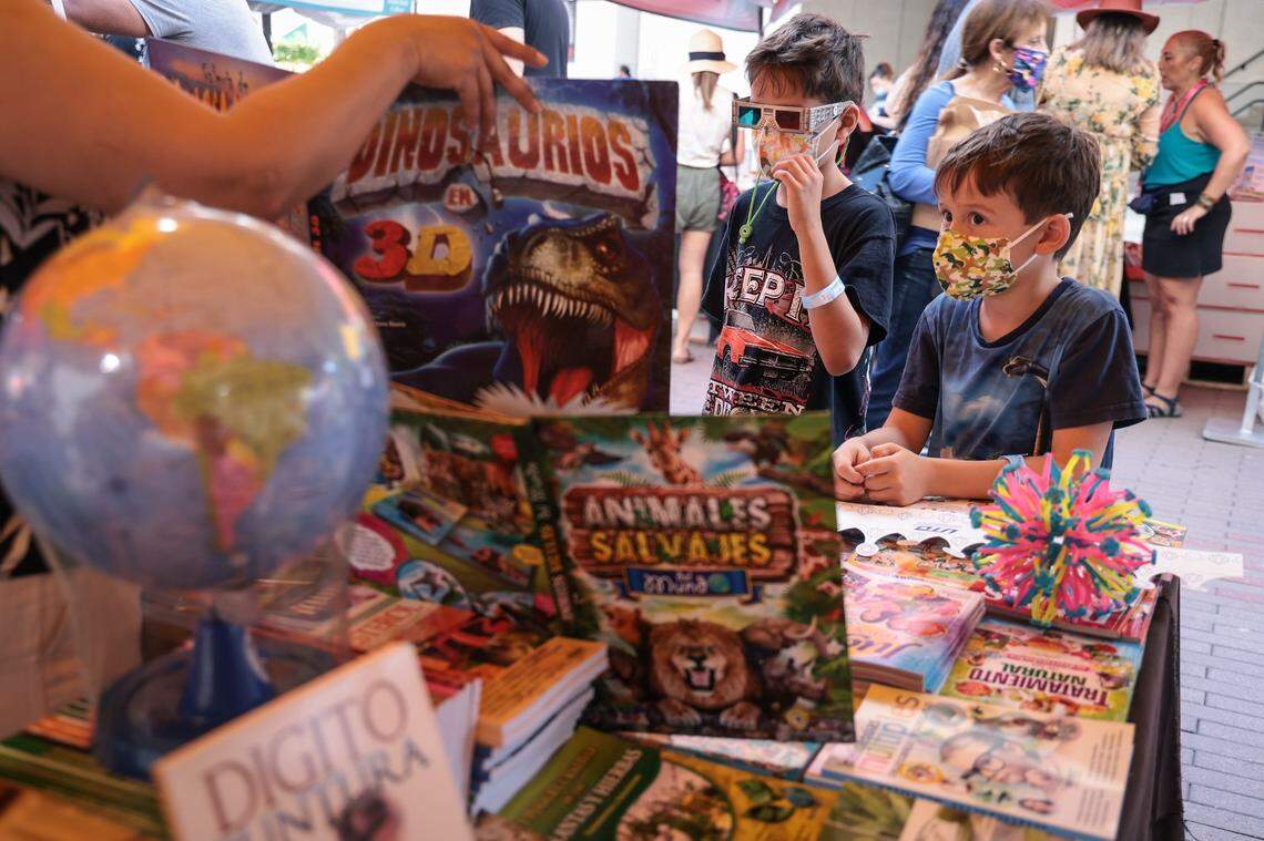 Brothers Valentino, 9, left, and Giacomo Patria, 6, sample the 3-D books at the Multilibros En Español booth at the 2021 Miami Book Fair. Children’s Alley will also have activities and appearances by beloved book characters for kids.