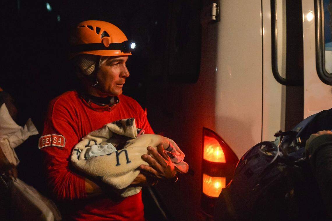 A Cuban firefighter holds a baby wrapped in a blanket during evacuations in the tornado-hit Luyano neighborhood in Havana early on January 28, 2019.