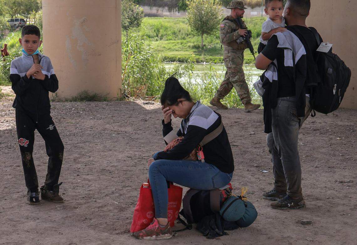 Venezolanos recién llegados esperan a la Patrulla Fronteriza después de cruzar el río Grande, mientras la Guardia Nacional de Texas patrulla la zona el 18 de septiembre de 2022.