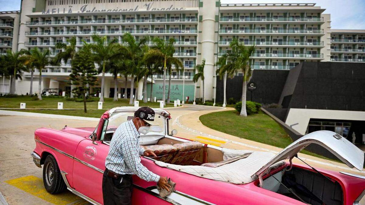 Un hombre limpia un viejo automóvil estadounidense frente a un hotel en Varadero, provincia de Matanzas, Cuba, el 22 de octubre de 2021. Yamil LAGE / AFP/ Getty Images